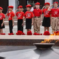 Dzieci w czerwonych beretach i koszulkach oddają hołd przy Wiecznym Ogniu. Utopijny i realny obraz rzeczywistości.