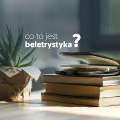Co to jest beletrystyka? Stos książek i notes z ołówkiem na biurku, obok rośliny.