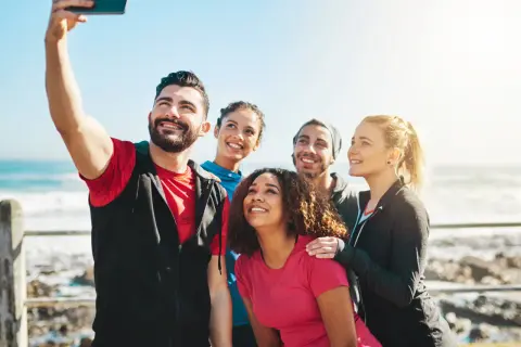 Grupa przyjaciół robi sobie selfie nad morzem. Ich uśmiechy to najlepsze cytaty o sobie, pełne radości i wspólnych chwil.