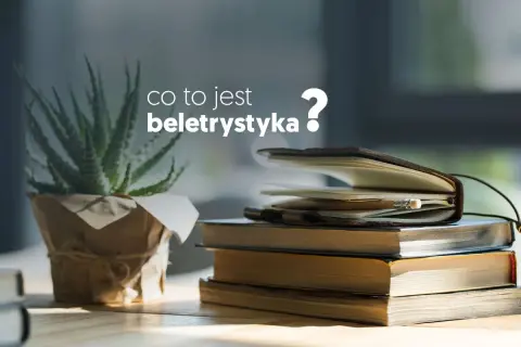 Co to jest beletrystyka? Stos książek i notes z ołówkiem na biurku, obok rośliny.