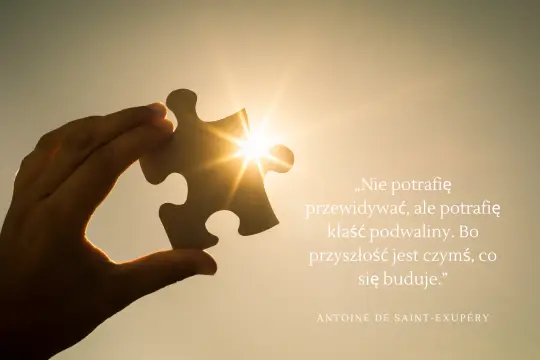Dłoń trzyma element układanki na tle zachodzącego słońca. Cytat Antoine'a de Saint-Exupéry'ego przypomina o budowaniu przyszłości, co jest jednym z najpiękniejszych życiowych cytatów.