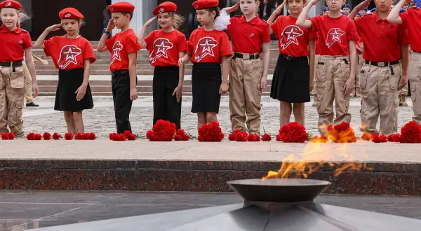 Dzieci w czerwonych beretach i koszulkach oddają hołd przy Wiecznym Ogniu. Utopijny i realny obraz rzeczywistości.