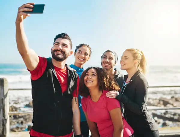Grupa przyjaciół robi sobie selfie nad morzem. Ich uśmiechy to najlepsze cytaty o sobie, pełne radości i wspólnych chwil.